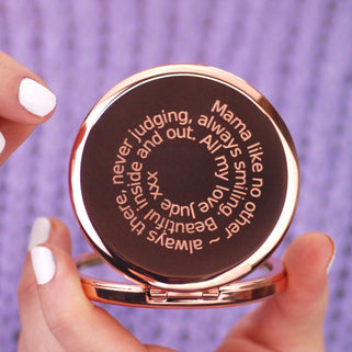 Rose gold compact mirror with personalised spiral message engraved on the front, shown in close up shot held by model.